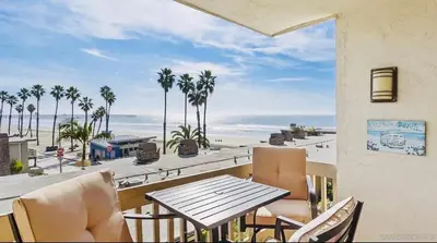 a table and chairs on a balcony with a view of the beach at Panoramic Ocean View Beachfront Condo in Oceanside