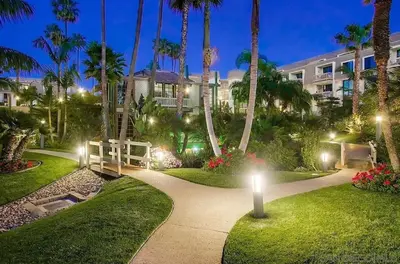 a walkway in a park with palm trees and a building at Panoramic Ocean View Beachfront Condo in Oceanside