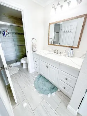 a white bathroom with a sink and a mirror at Panoramic Ocean View Beachfront Condo in Oceanside