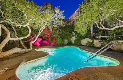 a swimming pool in a garden with trees at Panoramic Ocean View Beachfront Condo in Oceanside
