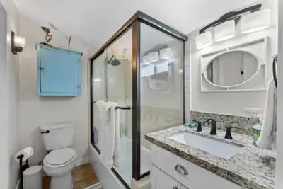 a white bathroom with a toilet and a sink at Lotus House by Coastline Vacation Rentals in San Diego