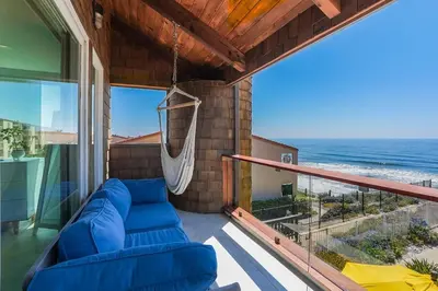 a porch with a blue couch and a hammock at Luxury Beachfront Townhouse with Breathtaking Views in Solana Beach