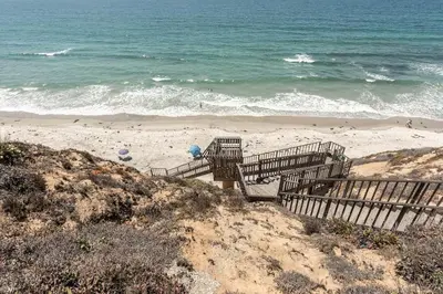 a sandy beach with stairs leading to the ocean at Luxury Beachfront Townhouse with Breathtaking Views in Solana Beach
