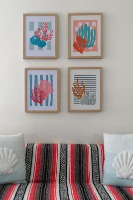 four framed pictures on a white wall with a couch at The Surf Shack by Coastline Vacation Rentals in San Diego
