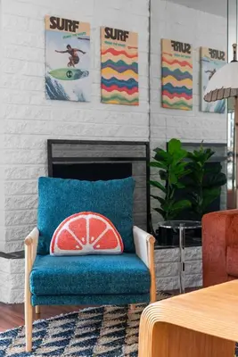 a living room with a blue chair with a surf pillow at The Wave by Coastline Vacation Rentals in San Diego