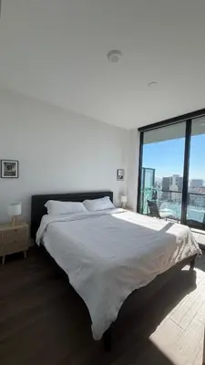 a white bedroom with a large bed and a large window at Little Italy, close to everything in San Diego