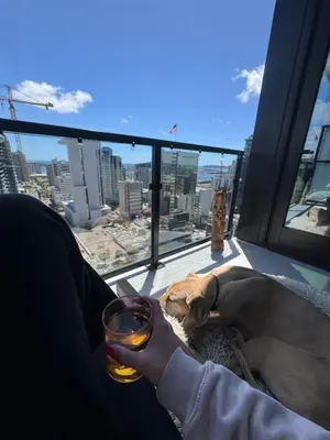 a person holding a glass of wine and a dog laying on a window at Little Italy, close to everything in San Diego