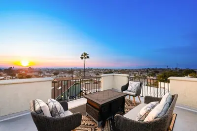 a balcony with chairs and a table and a sunset at The Lookout by Coastline Vacation Rentals in Chula Vista