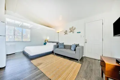 a bedroom with a bed and a couch and a tv at Beach Break by Coastline Vacation Rentals in San Diego