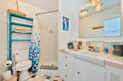 a bathroom with a sink and a toilet and a mirror at Beach Break by Coastline Vacation Rentals in San Diego