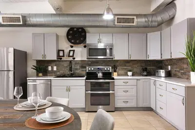 a kitchen with white cabinets and a table with chairs at SD Modern Rustic 3BR Apartment in San Diego