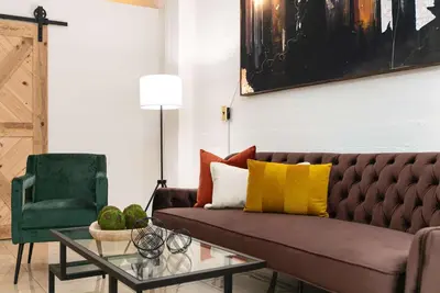 a living room with a brown couch and a green chair at SD Modern Rustic 3BR Apartment in San Diego