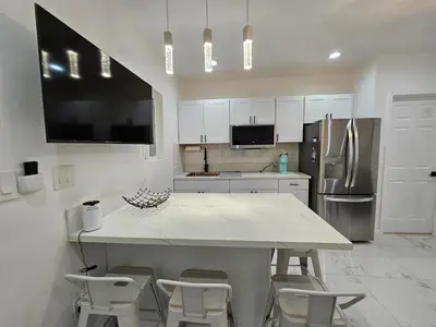 a kitchen with a large white island with stools at Modern Marble Retreat Private Gated ADU with Laundry & Parking in National City
