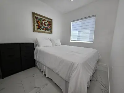 a white bedroom with a bed and a window at Modern Marble Retreat Private Gated ADU with Laundry & Parking in National City