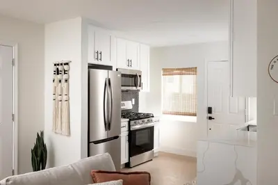 a white kitchen with a stainless steel refrigerator at The Outpost by Coastline Vacation Rentals in San Diego