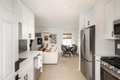 a kitchen with white cabinets and a living room at The Outpost by Coastline Vacation Rentals in San Diego
