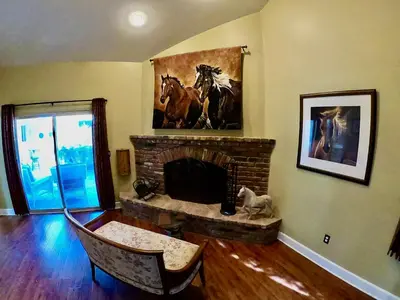 a living room with a fireplace with a painting of horses at Villa La Cresta - 5 Acre Retreat in Murrieta