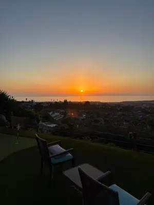 a sunset from a balcony with tables and chairs at Avenida Paradise! in San Clemente