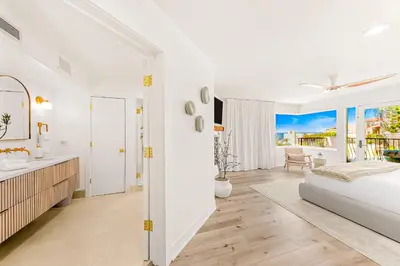 a white bedroom with a large bed and a bathroom at Sea & Sand - Ocean View La Jolla Condo in San Diego