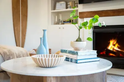 a coffee table with books and a potted plant on top at Sea & Sand - Ocean View La Jolla Condo in San Diego