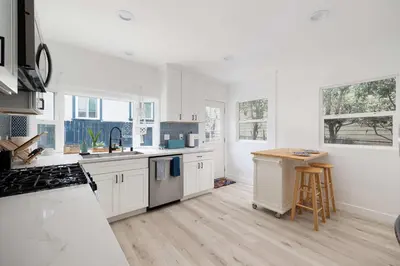 a kitchen with white cabinets and a wooden floor at Close to Balboa Park Central Villa in San Diego