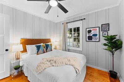 a bedroom with a white bed with a ceiling fan at The Ruby Door by Coastline Vacation Rentals in San Diego