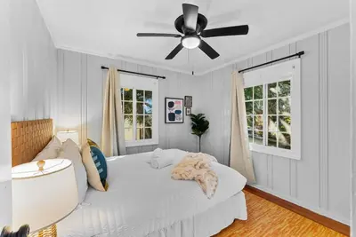 a bedroom with a white bed with a ceiling fan at The Ruby Door by Coastline Vacation Rentals in San Diego