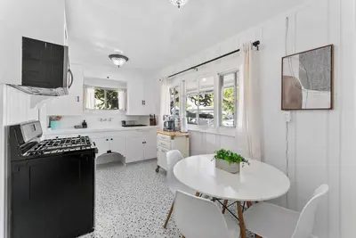 a white kitchen with a white table and a black stove at The Ruby Door by Coastline Vacation Rentals in San Diego