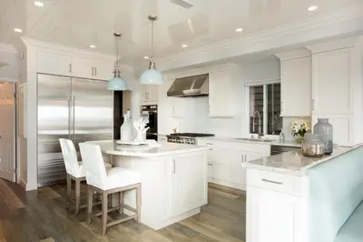 a kitchen with white cabinets and a island with white chairs at Newport Beach Oceanfront Home in Newport Beach