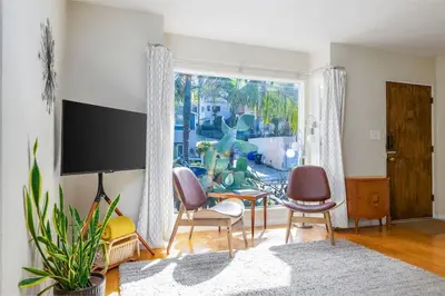 a living room with chairs and a table and a large window at Ocean Beach Bungalow - Close To Beach in San Diego
