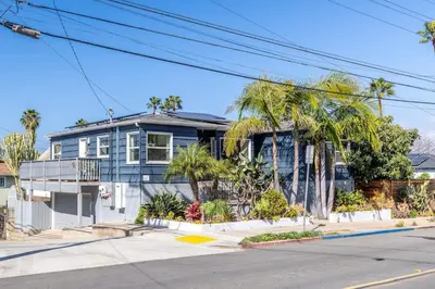 a blue house with palm trees in front of a street at Ocean Beach Bungalow - Close To Beach in San Diego