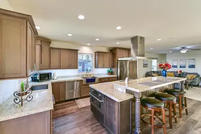 a kitchen with wooden cabinets and a large island with bar stools at Stroll to Shore Oceanside Condo with Hot Tub Access in Oceanside