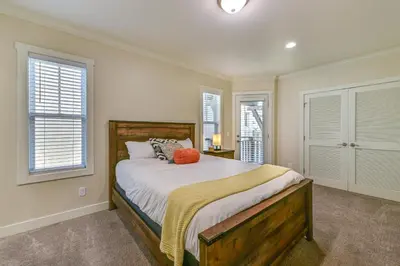 a bedroom with a bed and two windows at Stroll to Shore Oceanside Condo with Hot Tub Access in Oceanside