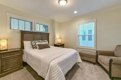 a bedroom with a bed and a chair and windows at Stroll to Shore Oceanside Condo with Hot Tub Access in Oceanside