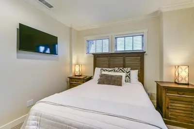 a bedroom with a large white bed and two windows at Stroll to Shore Oceanside Condo with Hot Tub Access in Oceanside
