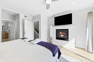 a white bedroom with a bed and a fireplace at Elevated Coastal Living | Rooftop Deck Steps from Beach & Restaurants in San Diego