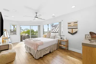 a white bedroom with a bed and a balcony at Elevated Coastal Living | Rooftop Deck Steps from Beach & Restaurants in San Diego