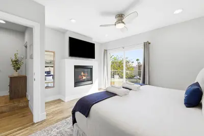 a white bedroom with a bed and a fireplace at Elevated Coastal Living | Rooftop Deck Steps from Beach & Restaurants in San Diego