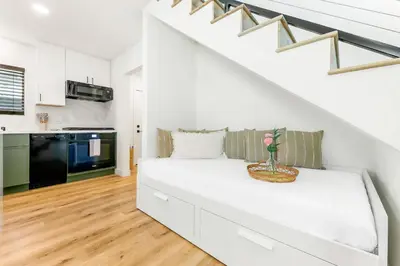 a white living room with a couch under the stairs at PB New Build - Steps to Sand & Surf in San Diego