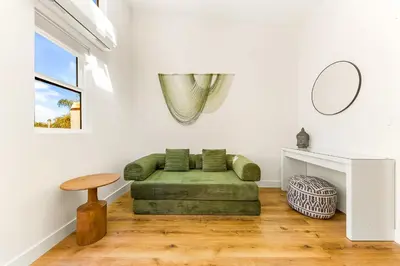a living room with a green couch and a table at PB New Build - Steps to Sand & Surf in San Diego