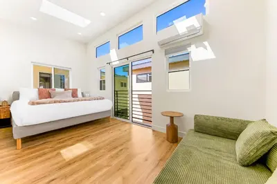 a bedroom with a bed and a couch and windows at PB New Build - Steps to Sand & Surf in San Diego