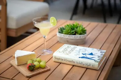 a table with a book and a glass of wine and cheese at PB New Build - Steps to Sand & Surf in San Diego