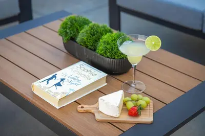a wooden table with a drink and a book and fruit at PB Beach Compound - 2 New Homes Steps to Sand in San Diego