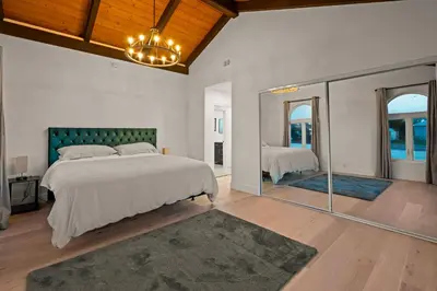 a bedroom with a large bed and a mirror at Spacious Modern Home with Rooftop & Private Backyard in Oceanside
