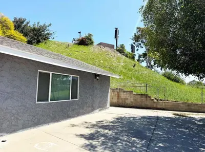 a house with a grassy hill behind it at Uniktrend Campo Rd Home by SD Stay in Spring Valley