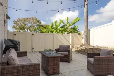 a patio with wicker chairs and tables and a fence at Spacious Central Home Villa in San Diego