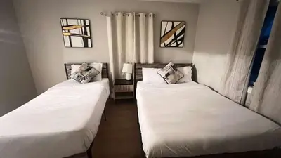 two beds in a room with white sheets and windows at 321 W Park El Cajon Front Unit by SD Stay in El Cajon