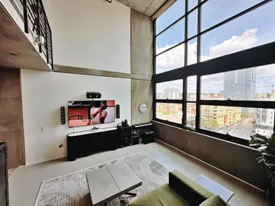 a living room with large windows and a couch at Penthouse Industrial Loft & Parking Little Italy in San Diego
