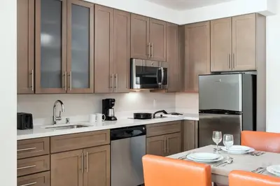 a kitchen with wooden cabinets and a table with orange chairs at Residence Inn by Marriott San Diego Downtown/Bayfront in San Diego