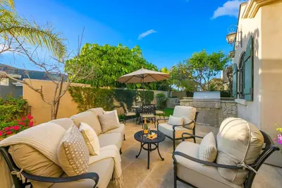 a patio with couches and tables and an umbrella at The Stratford - Del Mar Luxury Living in San Diego